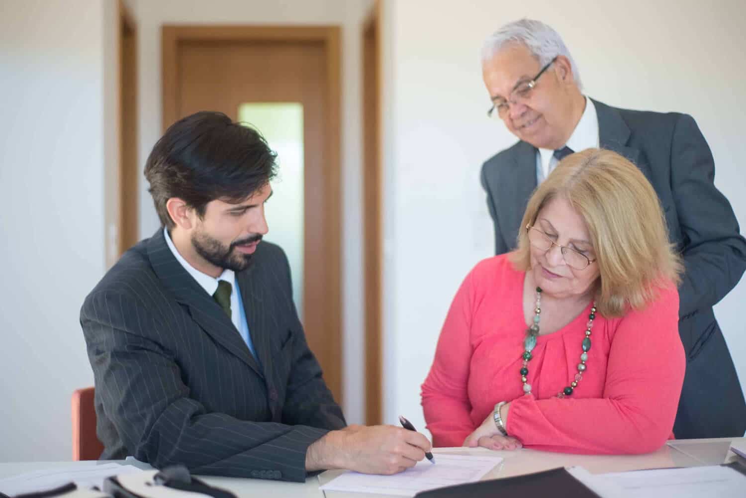 Femme signant un contrat devant un chef d'entreprise pour illustrer l'aide que peut apporter le coaching en entreprise dans le développement d'une société familiale